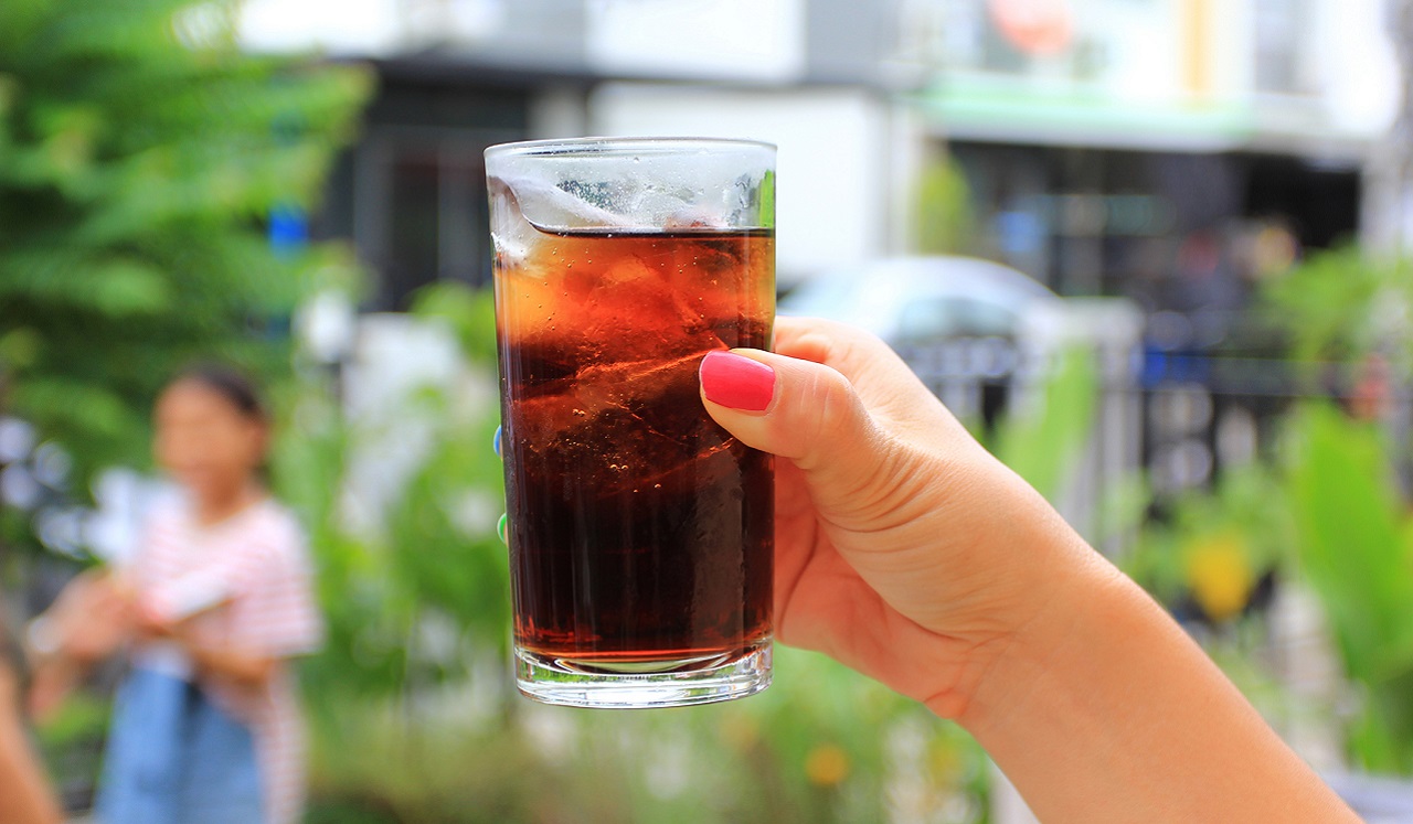 Woman's hand holding up a glass of soda.