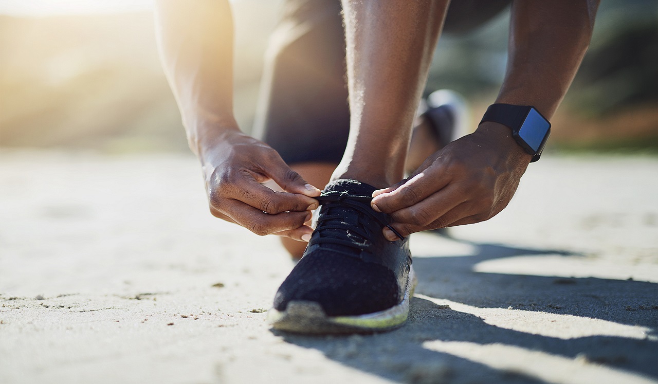 A jogger tying their shoe on a running trail.