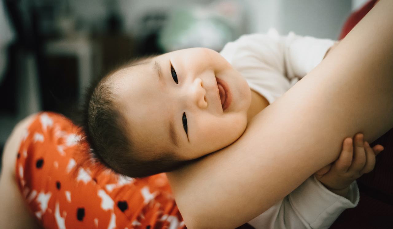 A smiling baby in mother's arms.