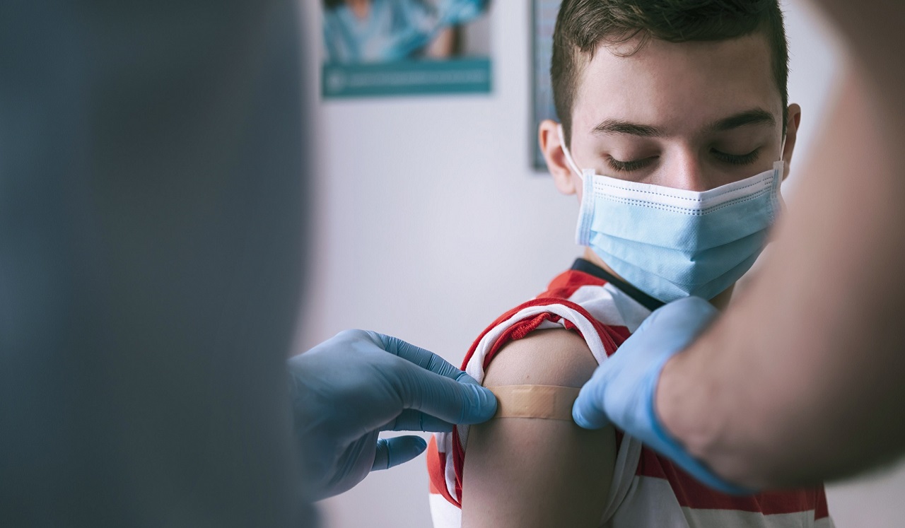 A young boy wearing a mask receives a vaccination.