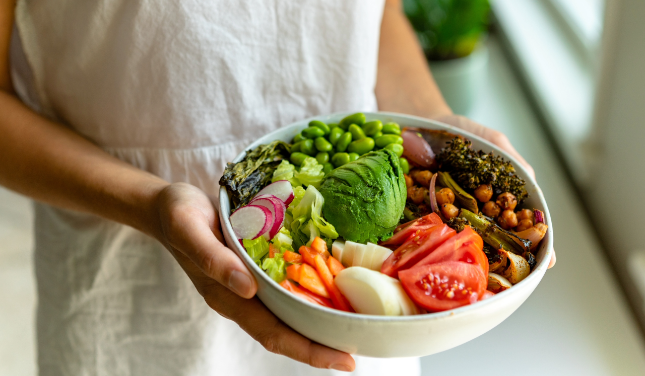 Person holding bowl of vegetables