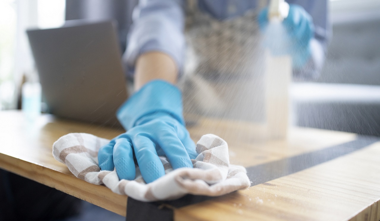 A gloved hand using a rag to wipe down a work surface.