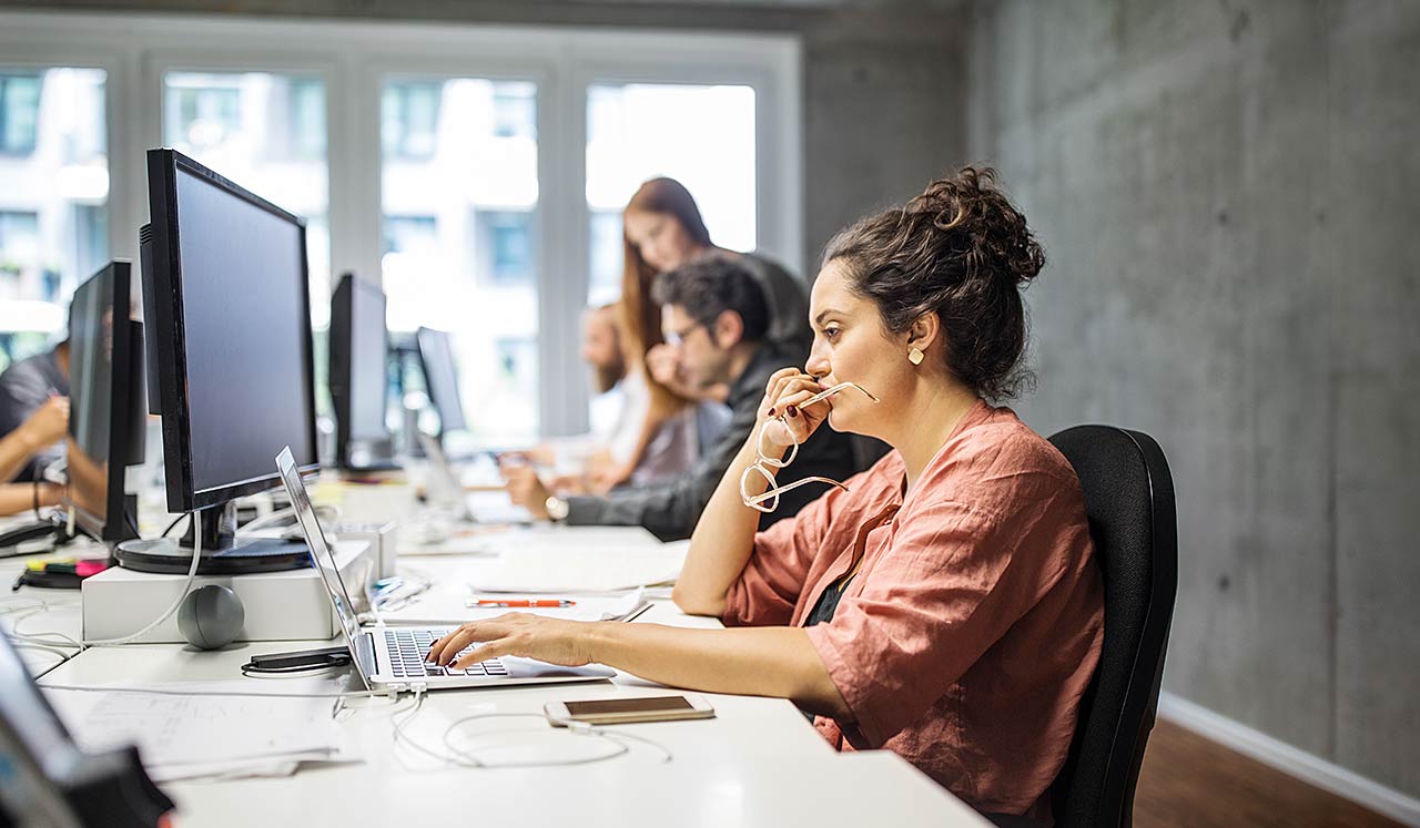 A woman in n office space looking at her computer.