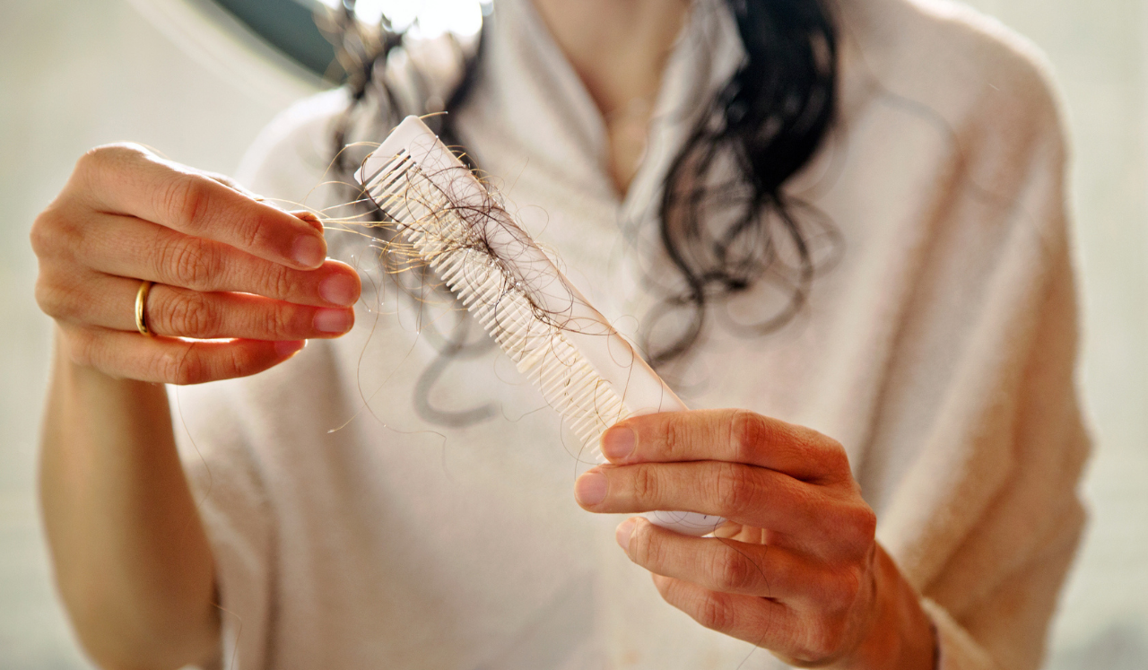 A woman in a bathrobe holding wet, fallen hairs.