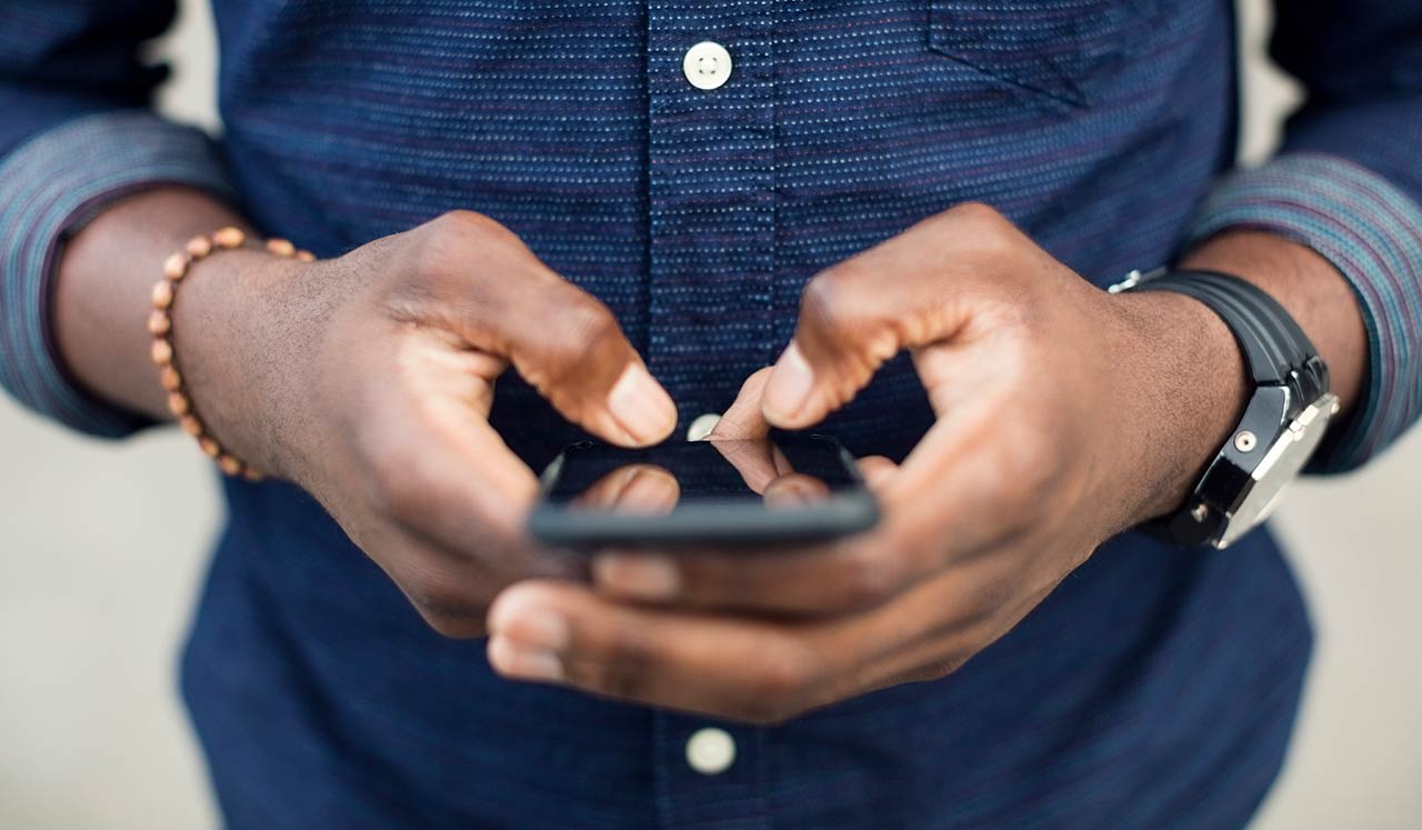 A man's hands holding a mobile phone.