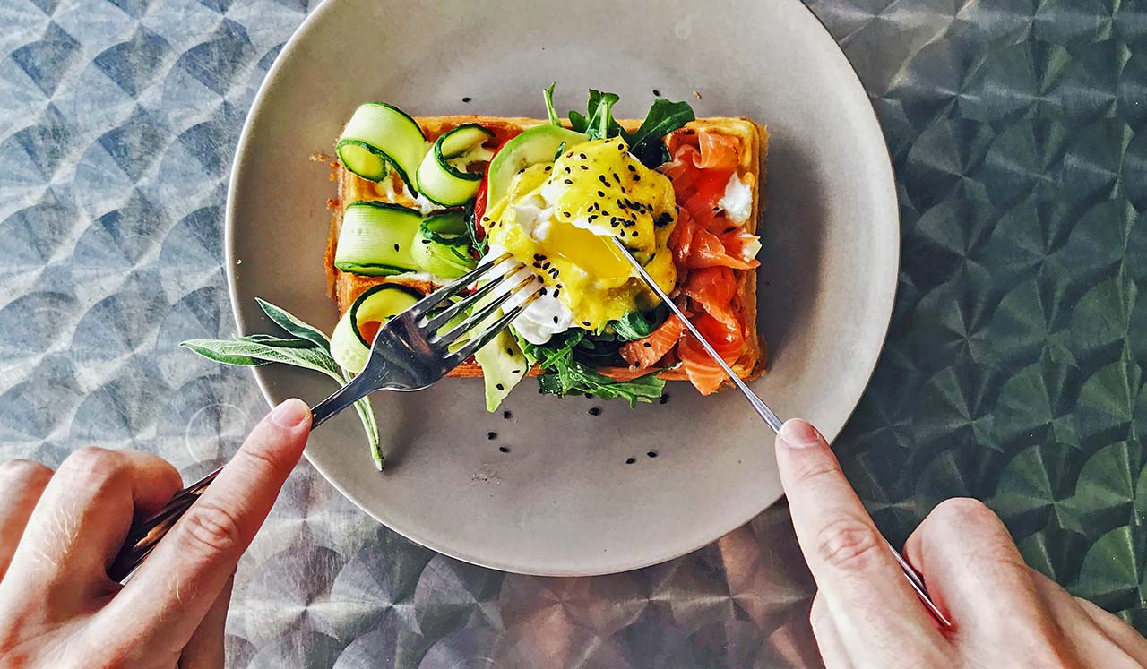 A breakfast food being cut with a fork and knife.