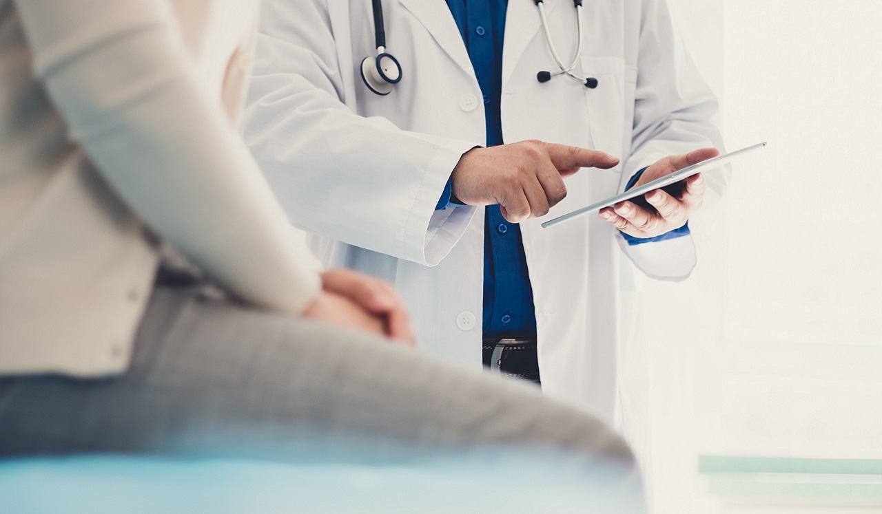 A person in a doctor's office speaking with a physician. 