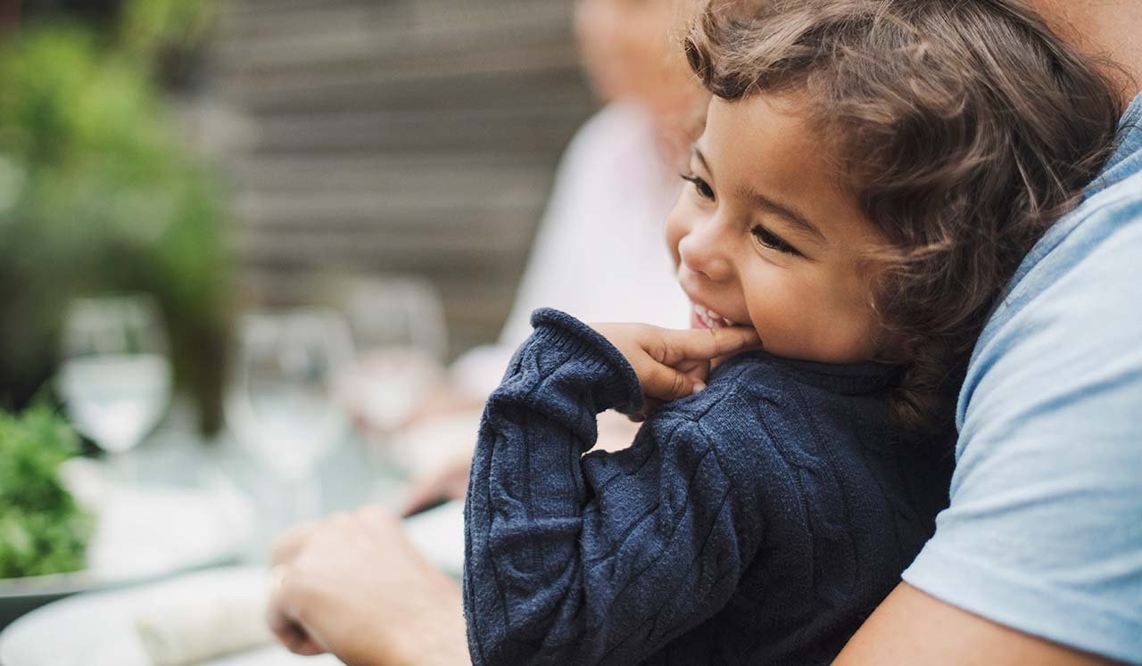 A smiling child being held by an adult.