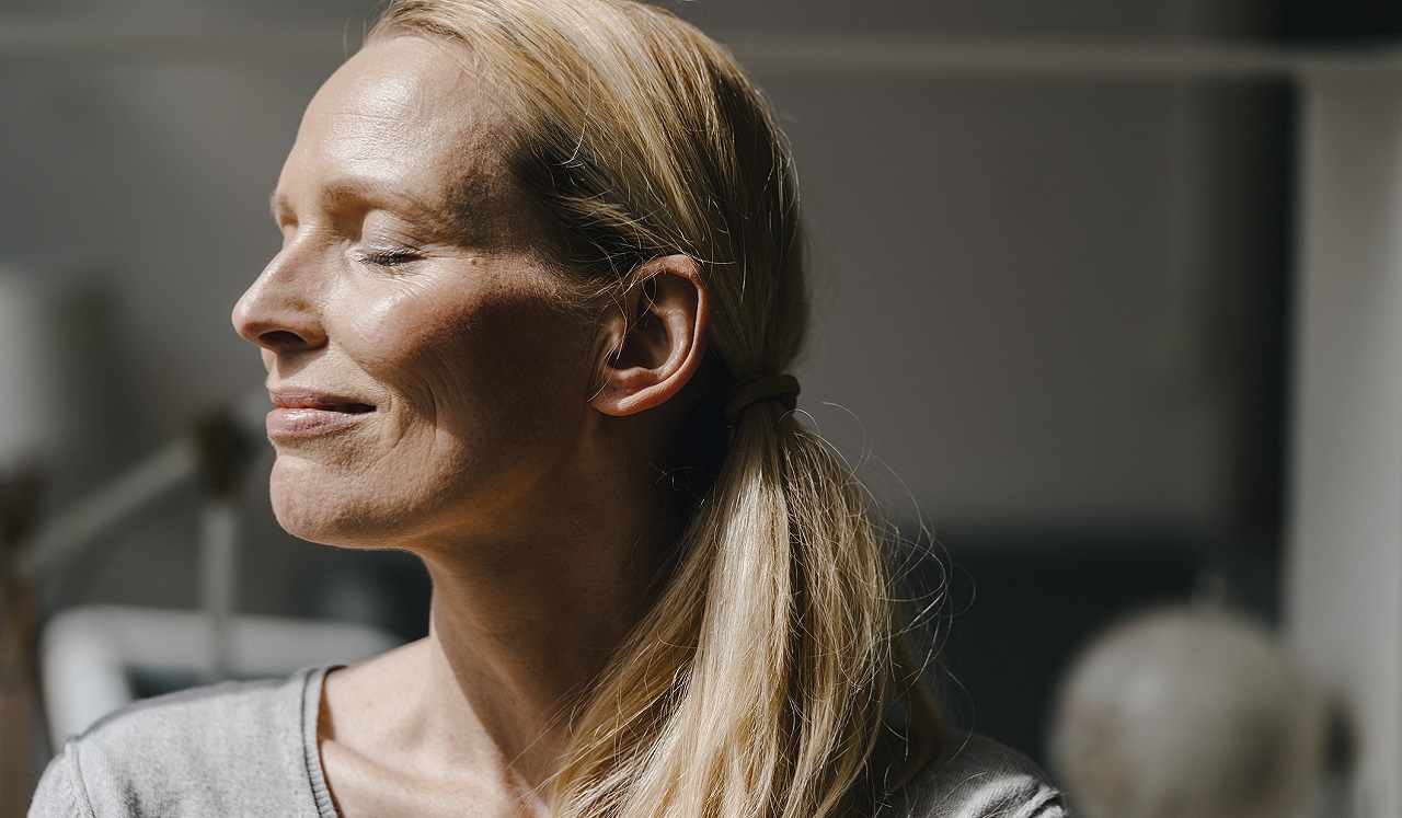 A woman smiling as the sun shines on her face. 