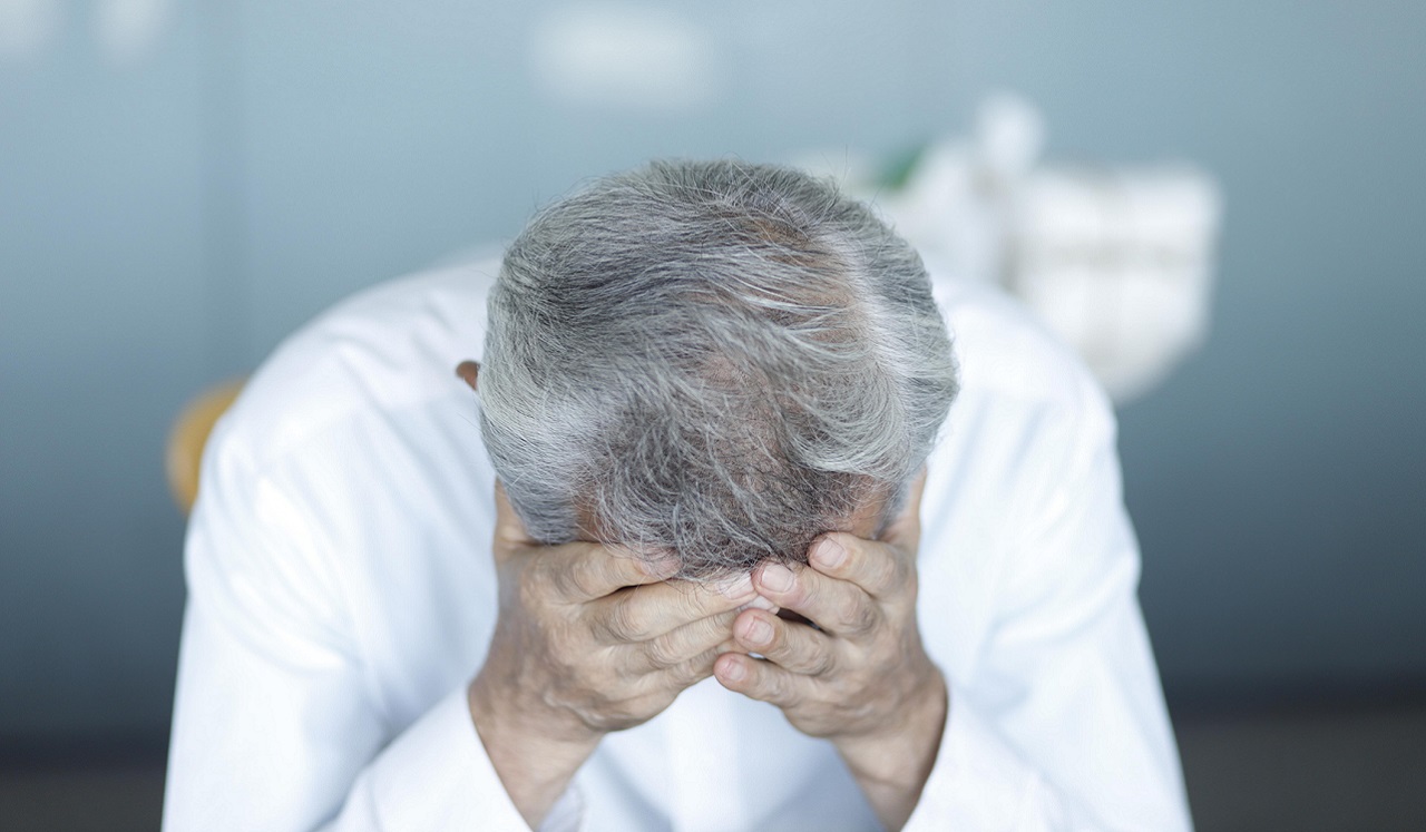 A person with their hands holding their forhead.