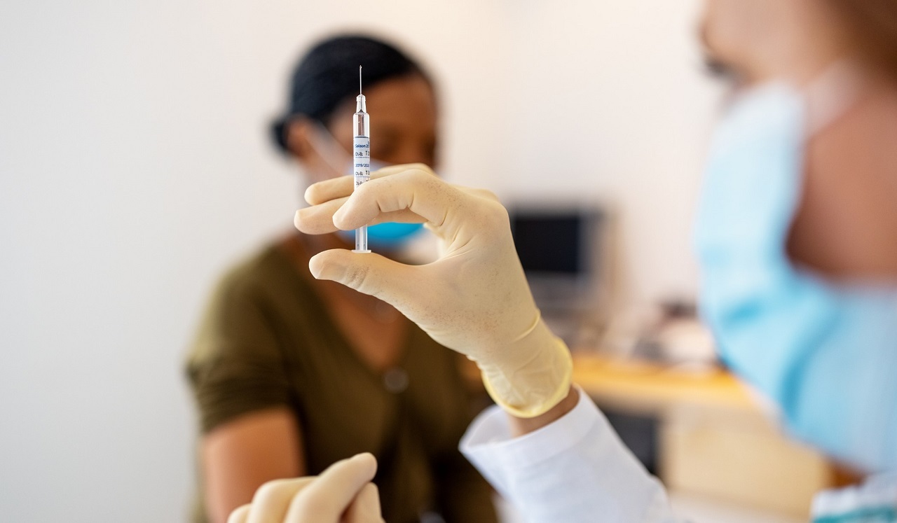 Medical staff prepares a vaccine for waiting patient.