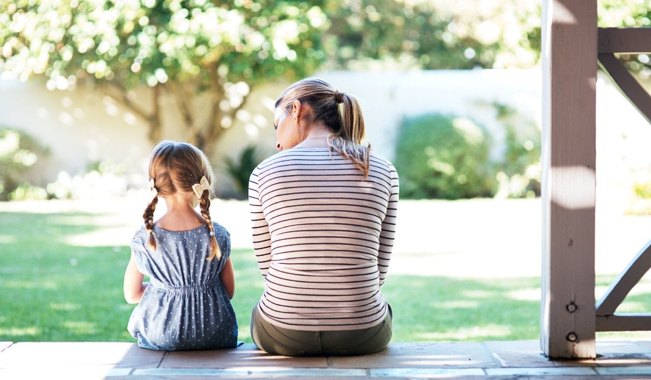 A mother and her child sitting on the porch having a thoughtful conversation.