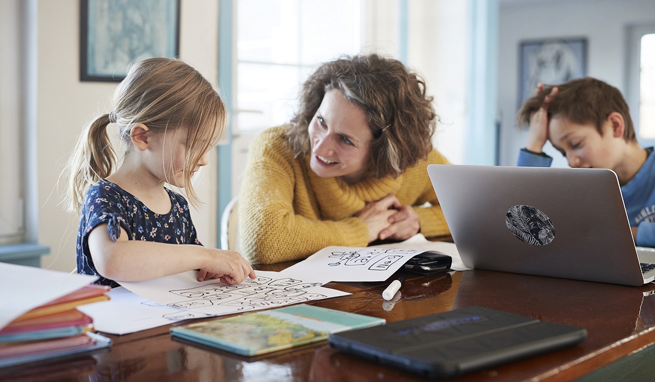 A mom and her children at the dining table doing school work.