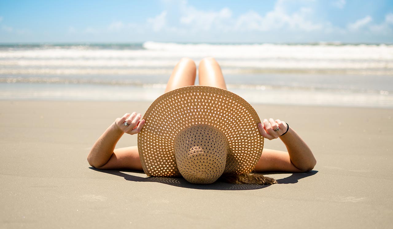 Woman in a hat lying on the beach