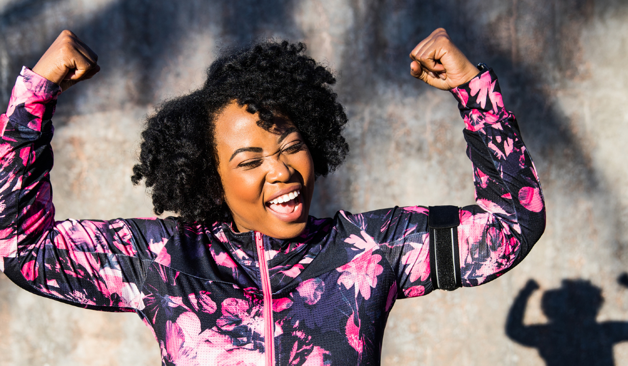 A woman in active wear flexing her biceps.