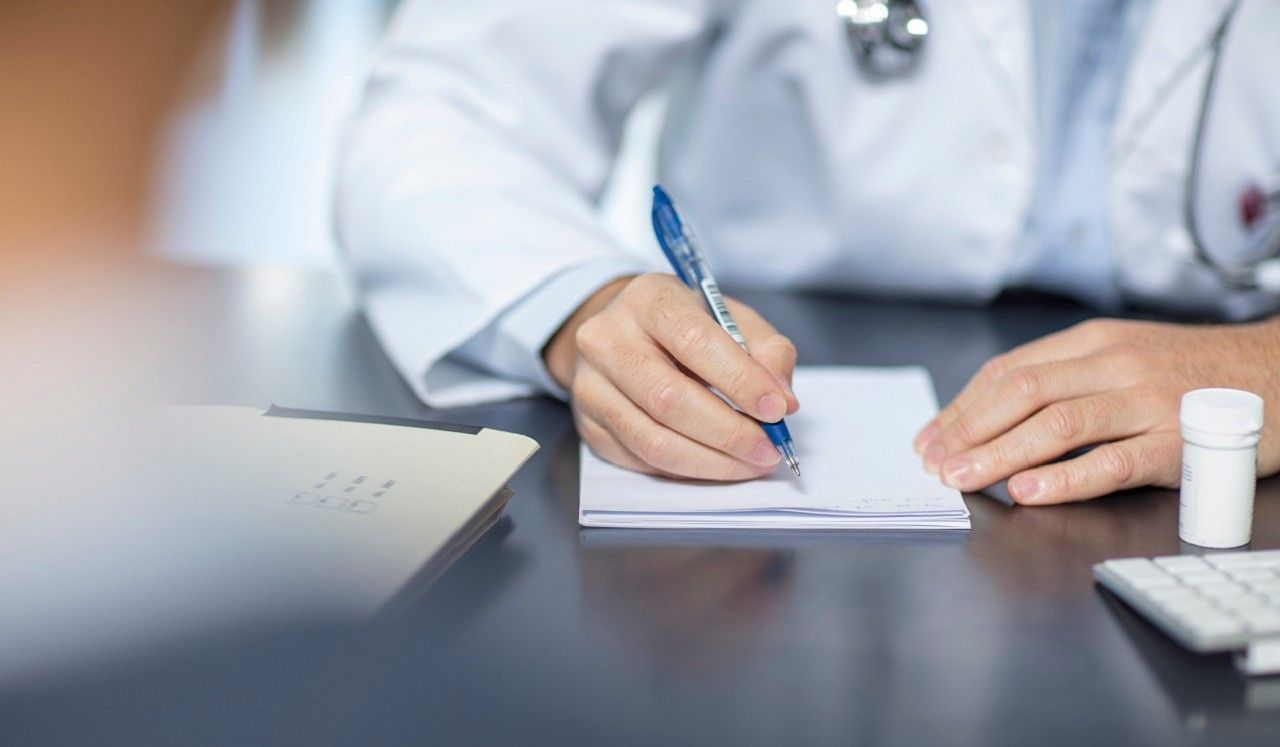 A physician making notes on a pad of paper.