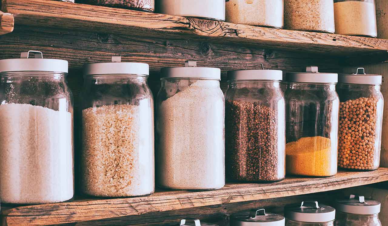 Glass canisters with white tops, filled with assorted grains.