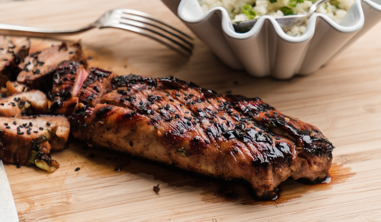 A grilled pork tenderloin topped with black sesame seeds.