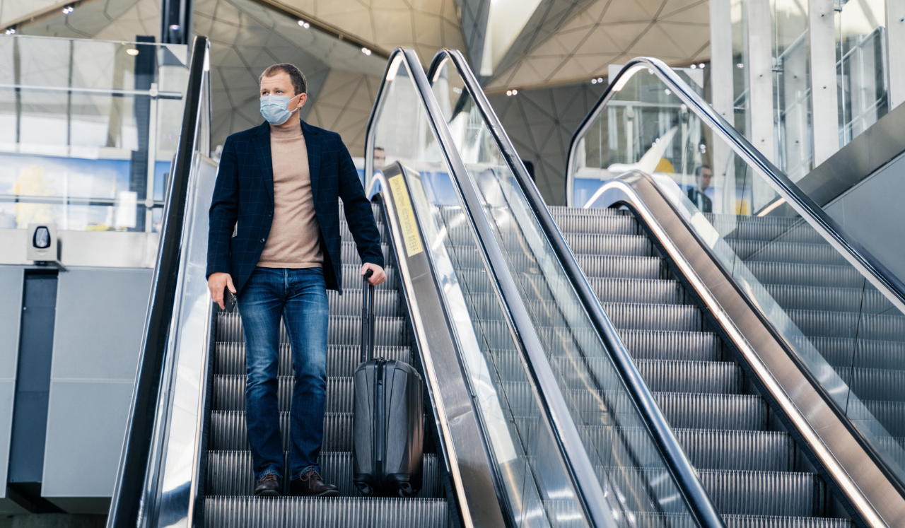 A man with a suitcase on an escalator.