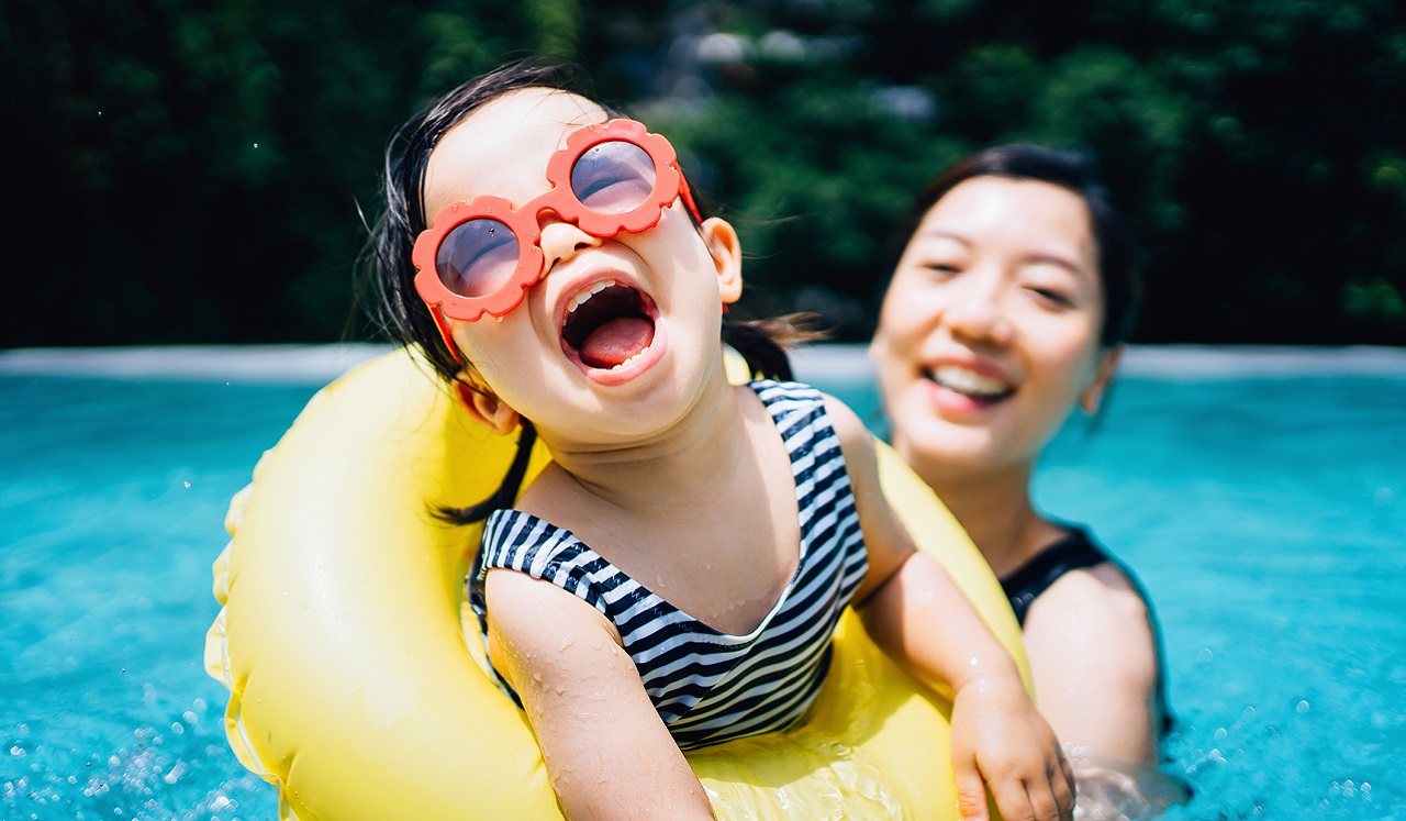 A mother and her toddler having fun in the swimming pool.