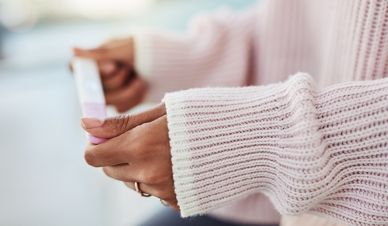 A woman holds a pregnancy test between her hands.