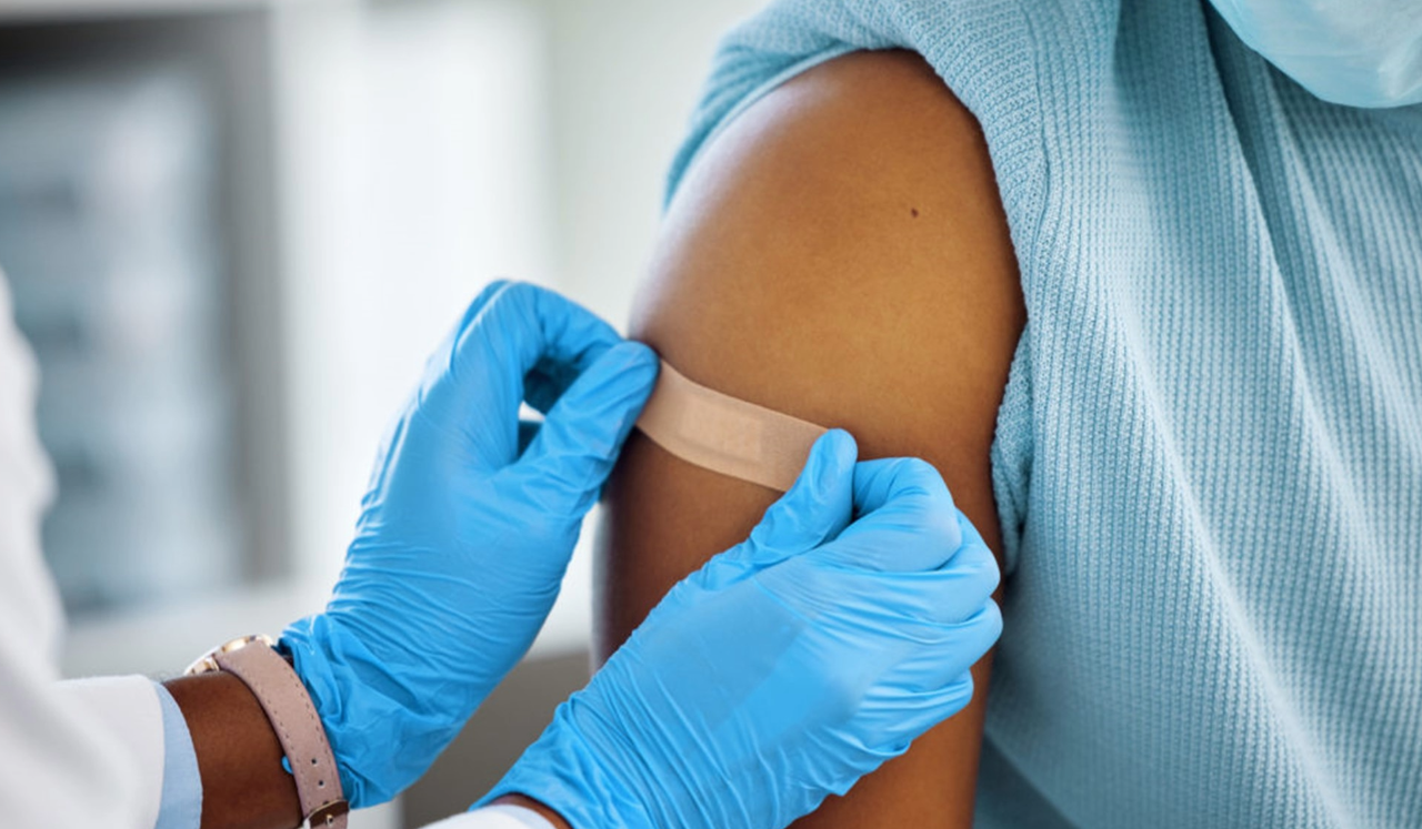 Doctor placing band-aid on patients shoulder