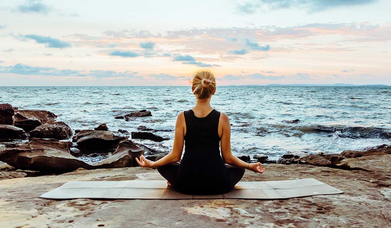 A woman meditating by the sea.