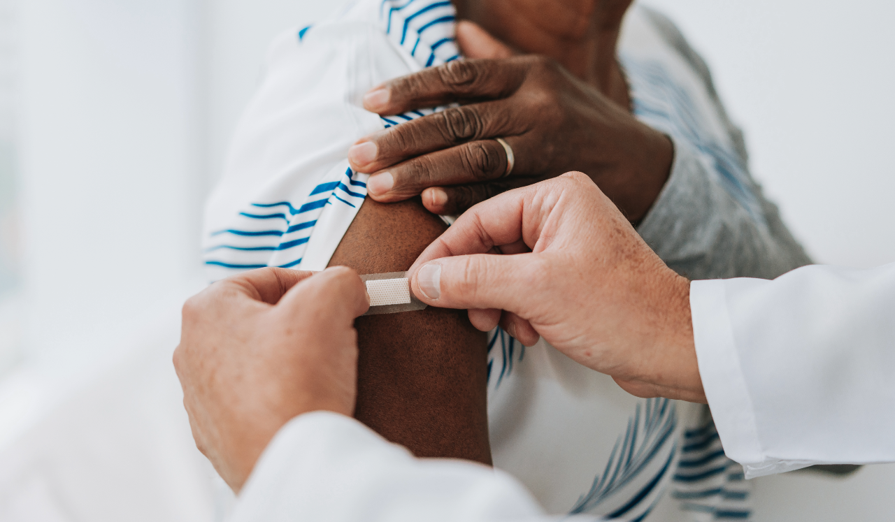 Person placing bandaid on arm after vaccine