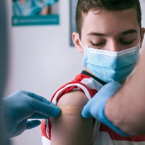 A young boy wearing a mask receives a vaccination.