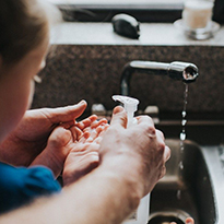 An adult and child using hand-over-hand instruction to wash hands.