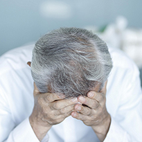 A person with their hands holding their forehead.