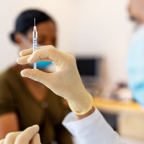 Medical staff prepares a vaccine for waiting patient.