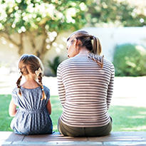 A mother and her child sitting on the porch having a thoughtful conversation.