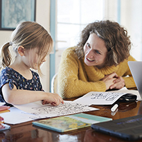 A mom and her children at the dining table doing school work.