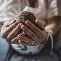 A new mother cupping her baby's head in her hands.