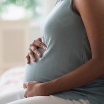 A pregnant woman holds her pregnancy belly with both hands.