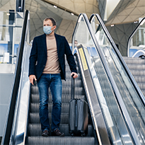 A man with a suitcase on an escalator.