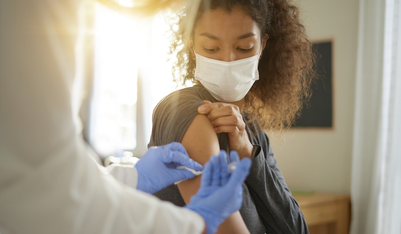 A vaccination record card and face mask on a table.