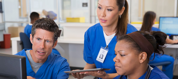 Nurses talking and looking at computer