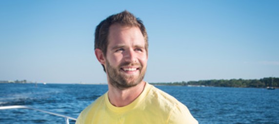 TIRR Memorial Hermann patient, James Durham, smiles while gazing out of the water from the bow of a boat. 