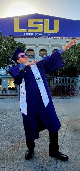 TIRR Memorial Hermann patient, Dallas Matamoros, poses in his graduation gown in front of Tiger Stadium.