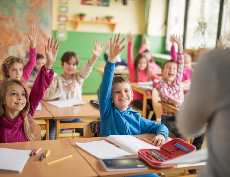 children raising hands in classroom