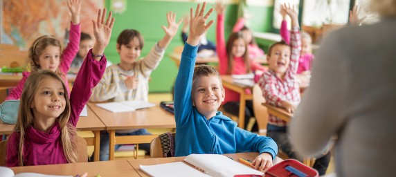 children raising hands in classroom