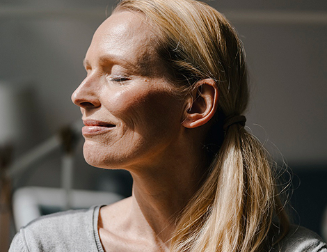 A woman smiling as the sun shines on her face