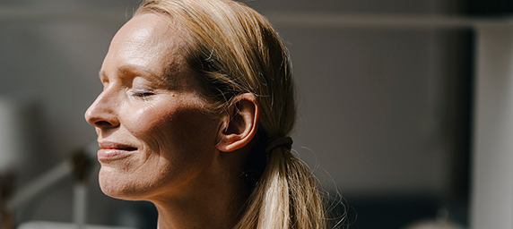 A woman smiling as the sun shines on her face