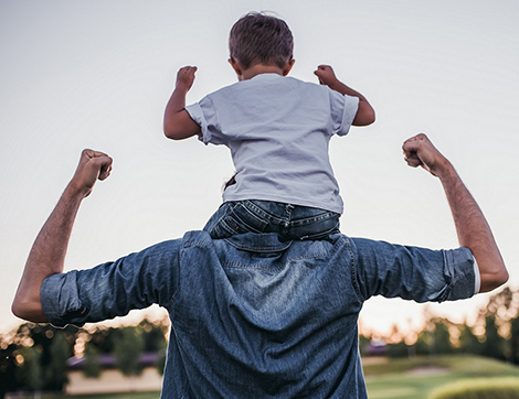 A child on his fathers shoulders outdoors