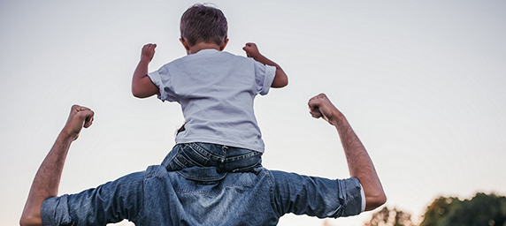 A child on his fathers shoulders outdoors