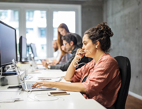 A woman in an office space looking at her computer