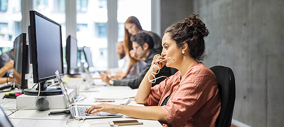 A woman in an office space looking at her computer