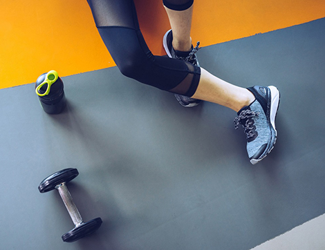 A woman and a hand weight on a workout mat